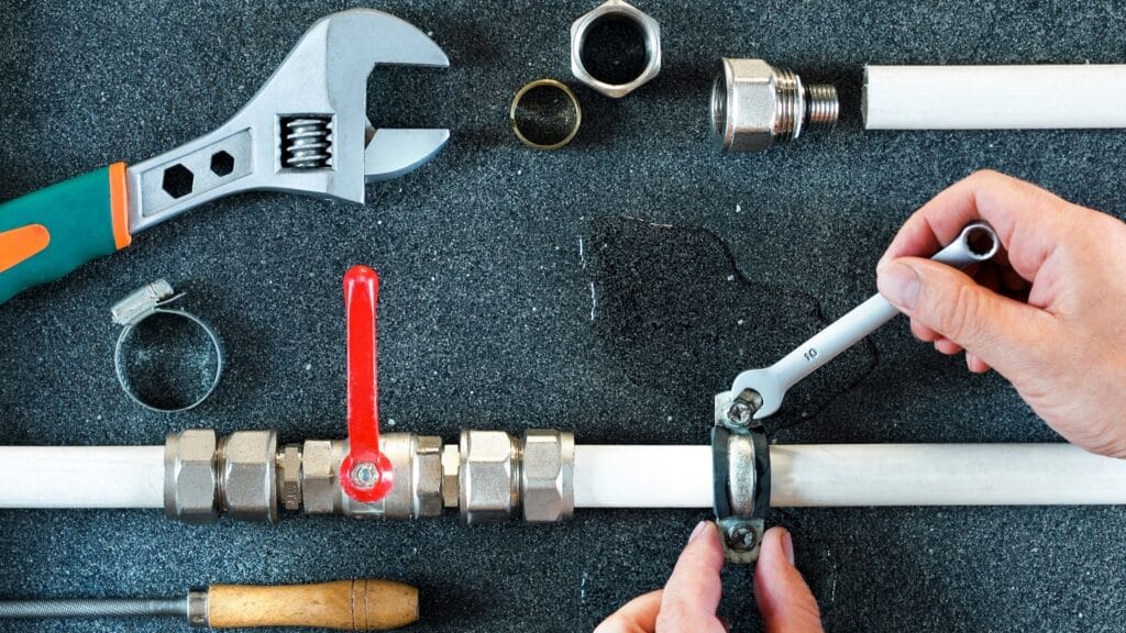 Plumber repairing a pipe valve with an adjustable wrench in Coral Springs