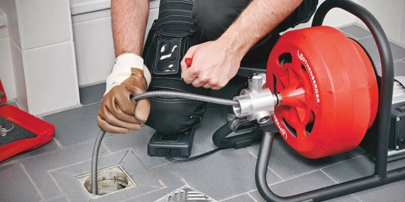 Plumber using a drain-cleaning machine in Coral Springs