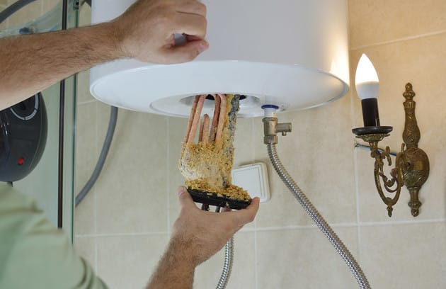 Technician removing mineral buildup from a water heater in Coral Springs