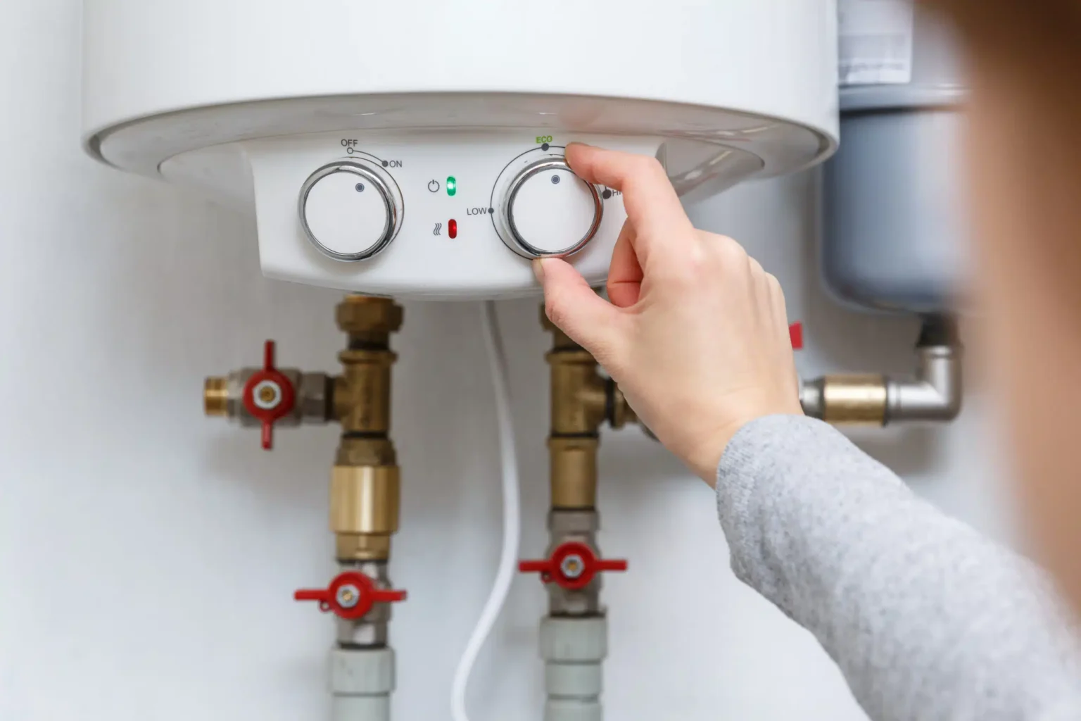 Homeowner adjusting the temperature controls on a water heater in Coral Springs